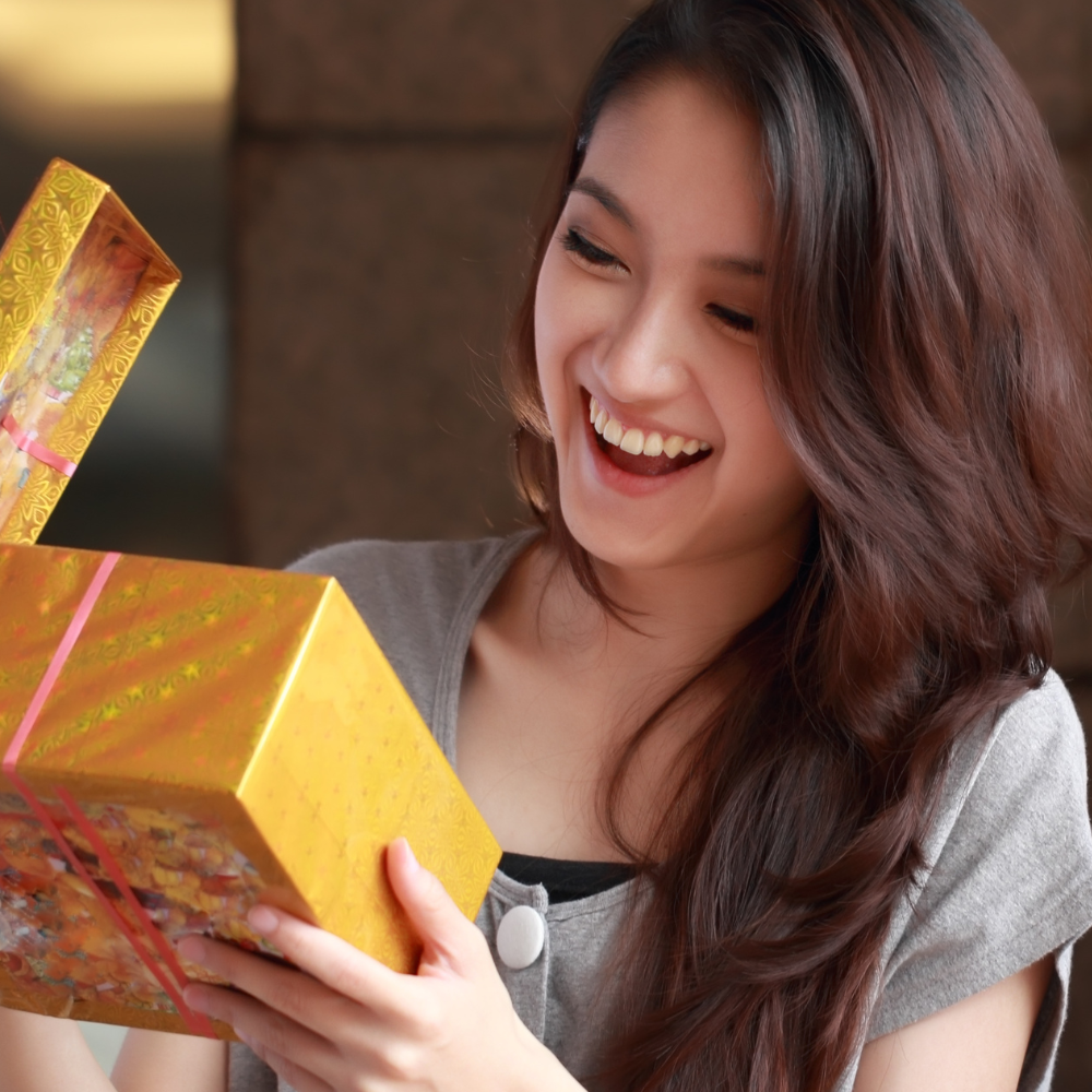 woman smiling while looking into a gift box