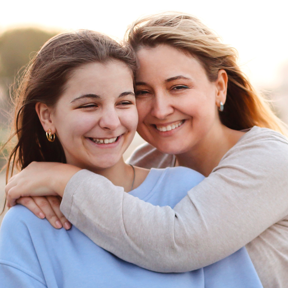 A mom and daughter smiling and hugging