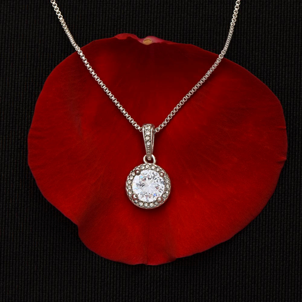 A diamond halo white gold necklace on a red rose petal