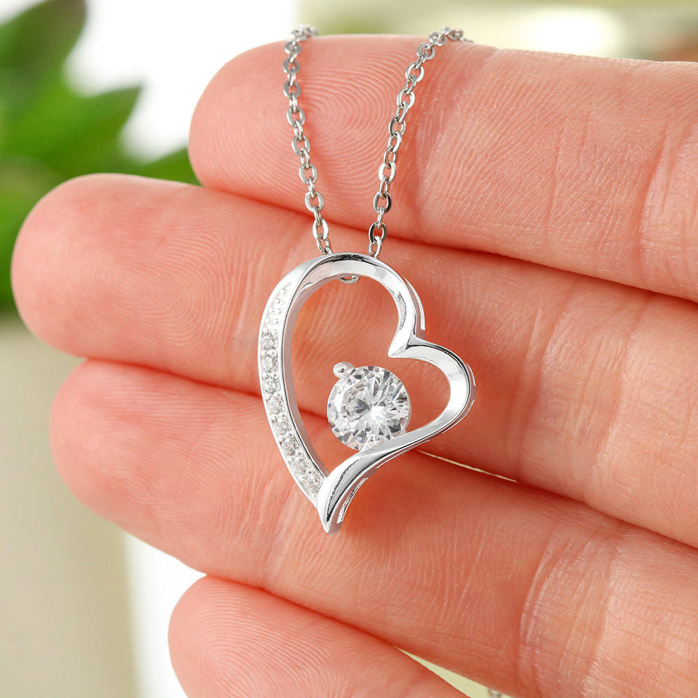 A close up view of a white gold heart necklace in hand