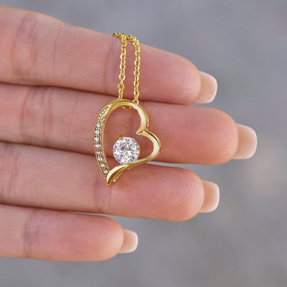 close up of yellow gold heart necklace in hand
