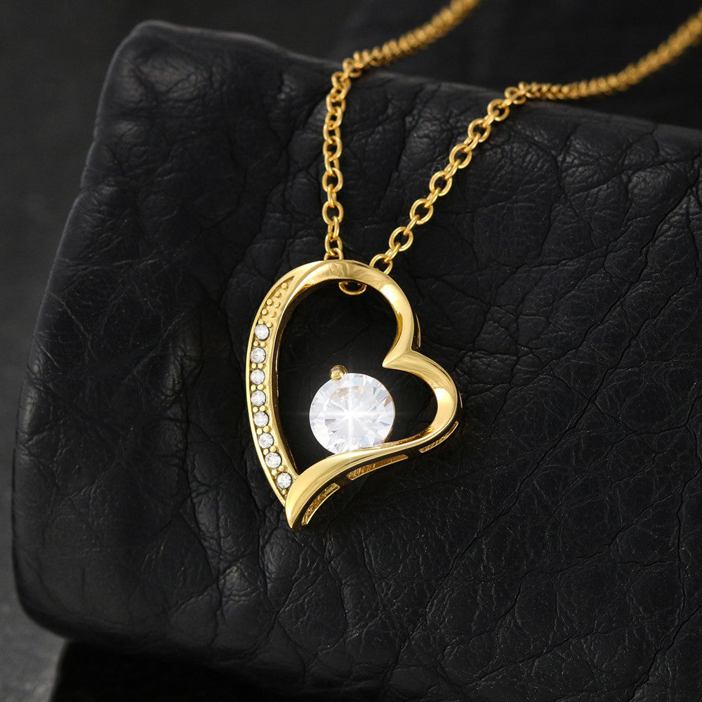 A yellow gold heart necklace up close on a black background