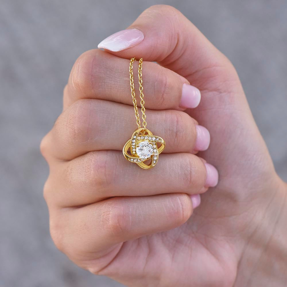 knot necklace in yellow gold close up in woman's hand