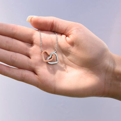 a hand holding the linked hearts rose and white gold necklace