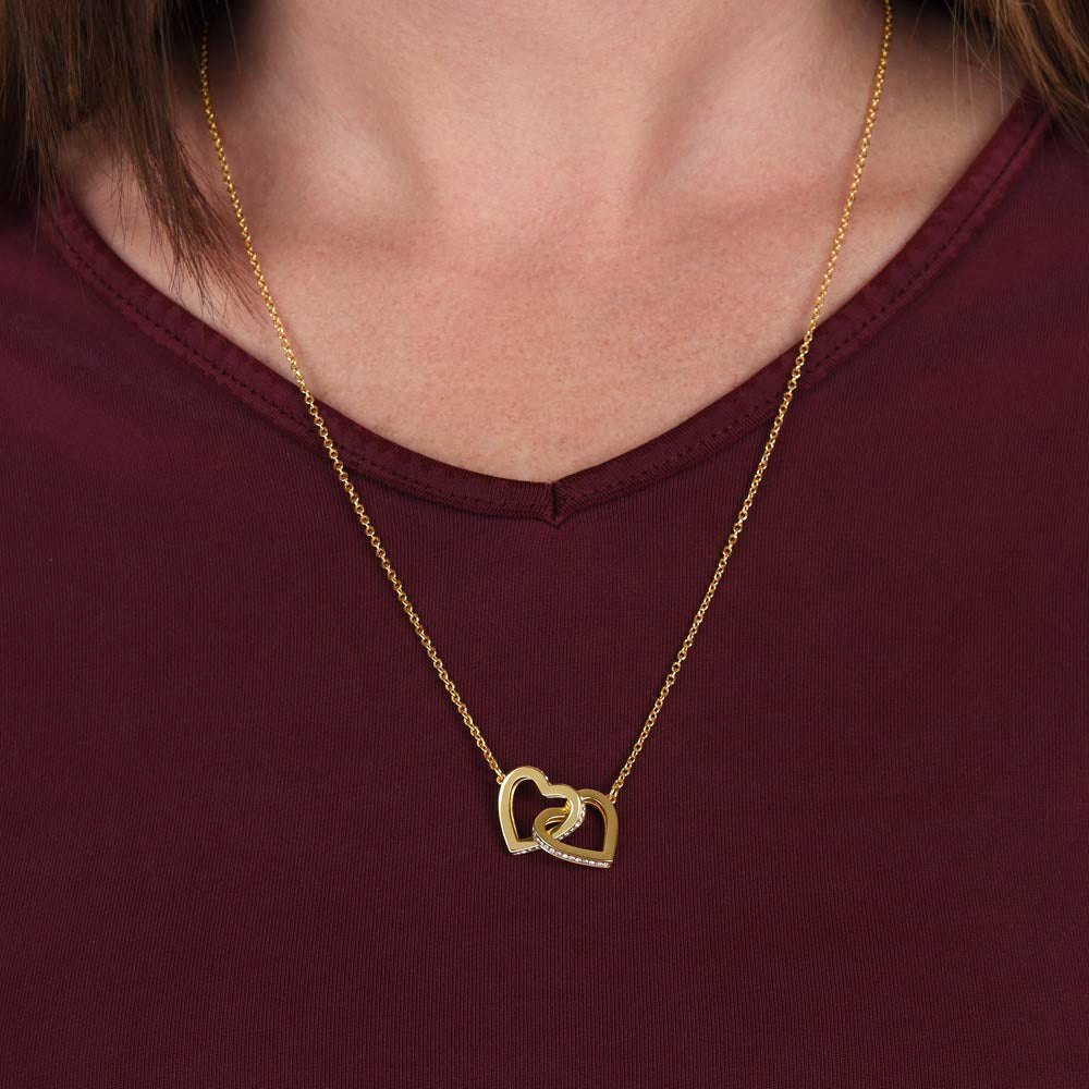 linked hearts yellow gold necklace against a woman's red shirt