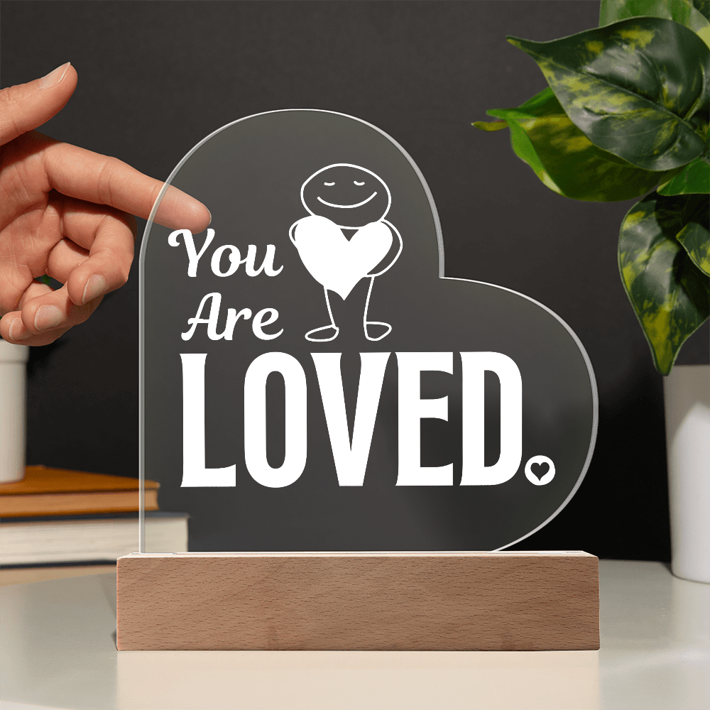 You are loved plaque with hand showing transparency against a black wall
