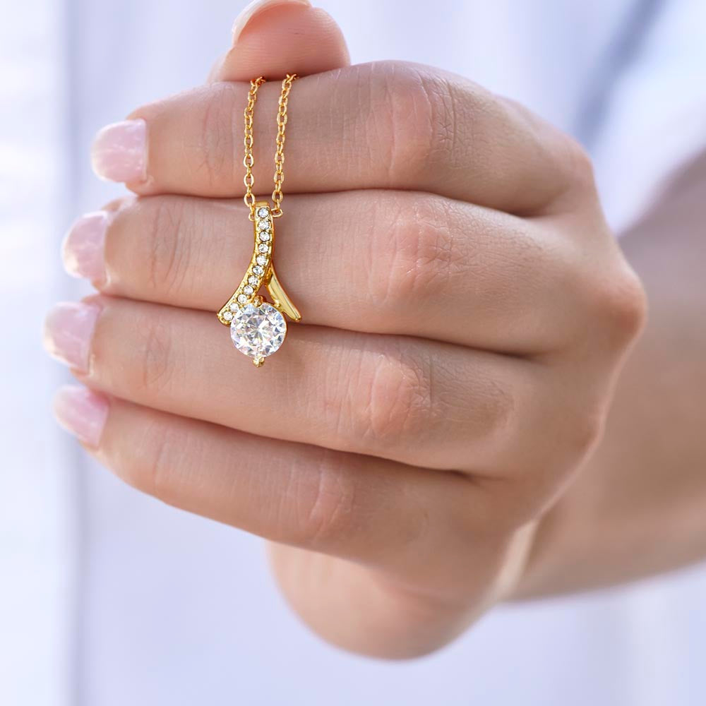 a yellow gold ribbon necklace held in woman's hand