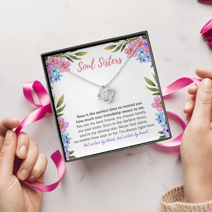 Soul sisters message card with white gold knot necklace and woman's hand with pink ribbon.