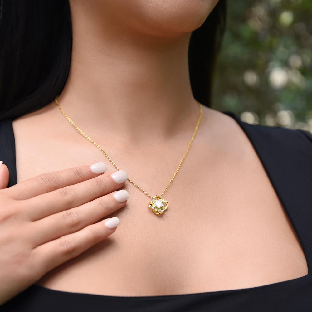 Yellow gold knot necklace on woman's neck.