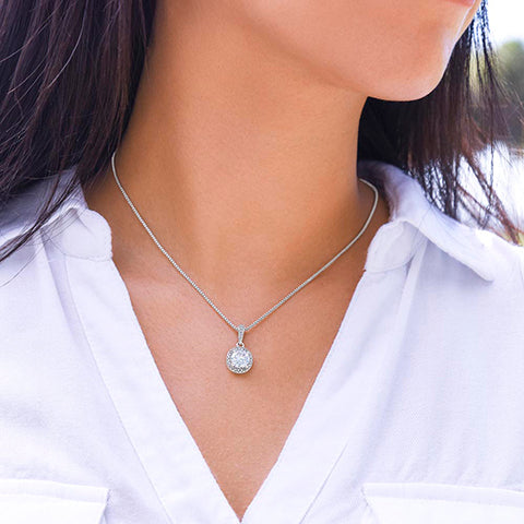 Silver necklace with a pendant worn by a person in a white shirt.