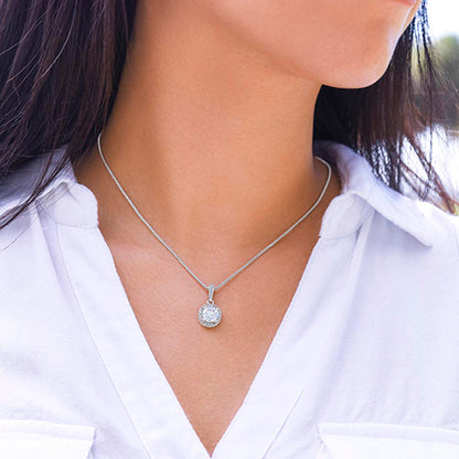 Silver necklace with a pendant worn by a person in a white shirt.